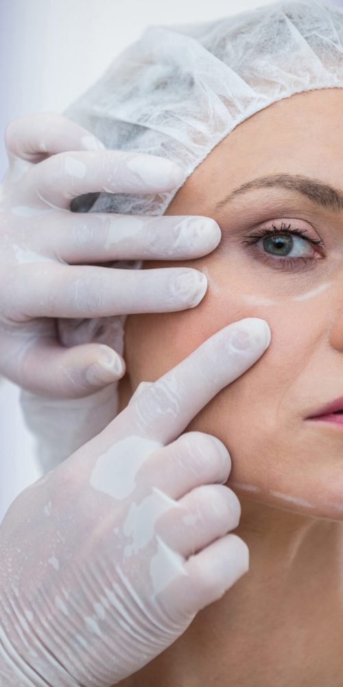 Close-up of doctor examining female patients face for cosmetic treatment